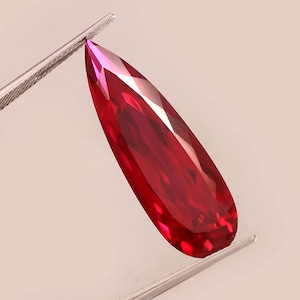 以下が含まれることがあります： ファセットカットされた深い赤色の洋梨型の宝石
