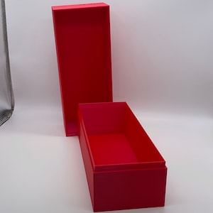 May include: A red rectangular box with a lid. The box is open and the lid is resting on the side.