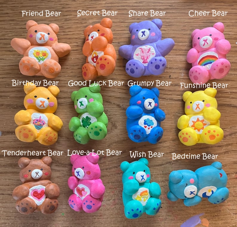 May include: Twelve colorful Care Bear figurines with different designs and names. Each bear has a unique color and symbol on its chest. The bears are arranged in three rows of four.