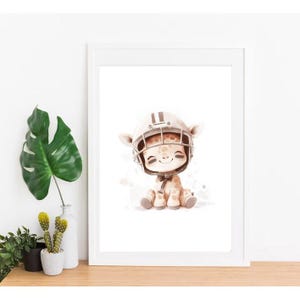 May include: A white framed print featuring a cartoon illustration of a giraffe wearing a brown and white football helmet. The giraffe is sitting on a white background with brown watercolor splatters.