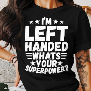 May include: Black t-shirt with white text that reads "I'm Left Handed - Whats Your Superpower?"
