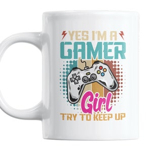 May include: White ceramic mug with a colorful design featuring a video game controller and the text "Yes I'm a Gamer Girl Try to Keep Up".