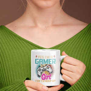 May include: White ceramic mug with a colorful graphic of a video game controller and the text "Yes I'm a Gamer Girl Try to Keep Up".