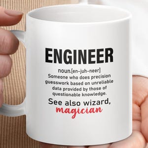 May include: White ceramic mug with a black and red design. The mug features the word "Engineer" with a definition and the words "See also wizard, magician".