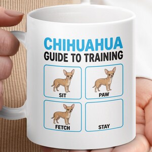 May include: White ceramic mug with the text "Chihuahua Guide to Training" in blue and black. The mug features illustrations of a Chihuahua with the commands "Sit," "Paw," "Fetch," and "Stay."
