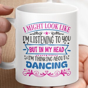 May include: White ceramic mug with a pink, blue and black design. The text on the mug reads "I might look like I'm listening to you, but in my head I'm thinking about dancing."