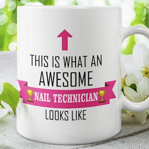 May include: White ceramic mug with a pink ribbon and gold trophy accents. The text on the mug reads "This is what an awesome nail technician looks like".