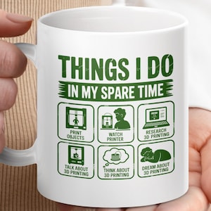 May include: White ceramic mug with the text "THINGS I DO IN MY SPARE TIME" in green. The mug features icons related to 3D printing, including printing objects, watching a printer, and researching 3D printing.