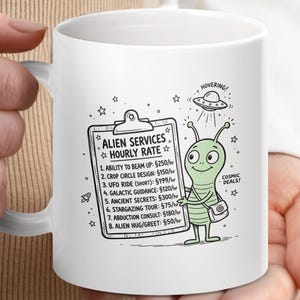 May include: White ceramic mug with a cartoon alien design. The mug features a list of "Alien Services Hourly Rate" and is held by a person. The mug has a white handle.