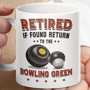 May include: White ceramic mug with a brown and white design. The mug reads "Retired If Found Return To The Bowling Green" with a graphic of three black and white bowls.