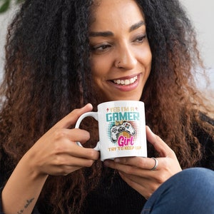 May include: White ceramic mug with a colorful design featuring a video game controller and the text "Yes I'm a Gamer Girl Try to Keep Up".