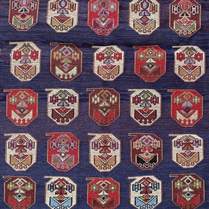 Op de afbeelding: Een herhalend patroon van achthoekige vormen met ingewikkelde geometrische ontwerpen in tinten rood, bruin, cr&egrave;me en blauw op een donkerblauwe achtergrond.