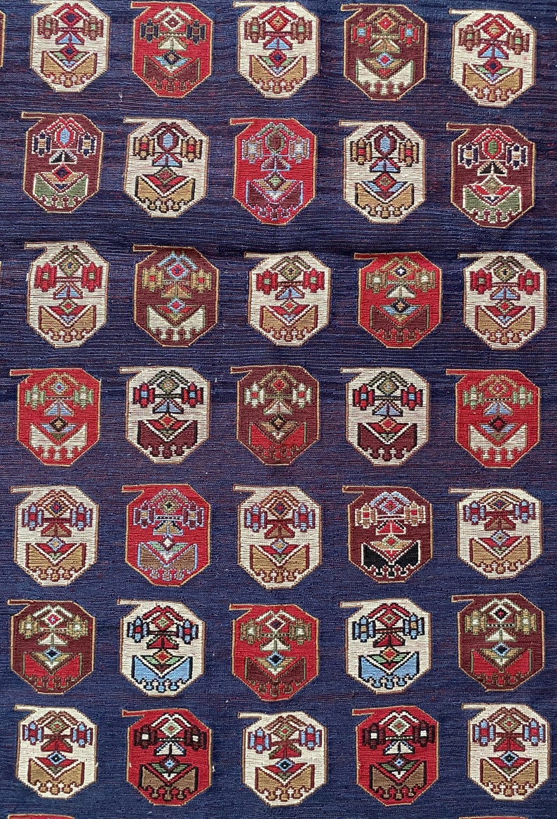 Op de afbeelding: Een herhalend patroon van achthoekige vormen met ingewikkelde geometrische ontwerpen in tinten rood, bruin, cr&egrave;me en blauw op een donkerblauwe achtergrond.