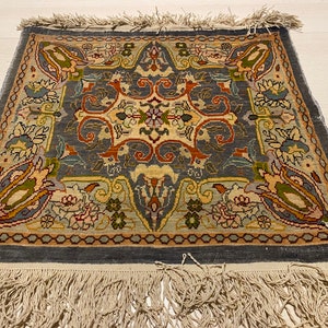 May include: A vintage rug with a blue background and intricate floral patterns in shades of brown, green, and cream. The rug has a fringe border.