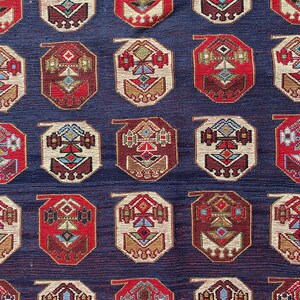 Op de afbeelding: Een herhalend patroon van achthoekige vormen met ingewikkelde geometrische ontwerpen in tinten rood, wit, blauw, bruin en goud op een donkerblauwe achtergrond.
