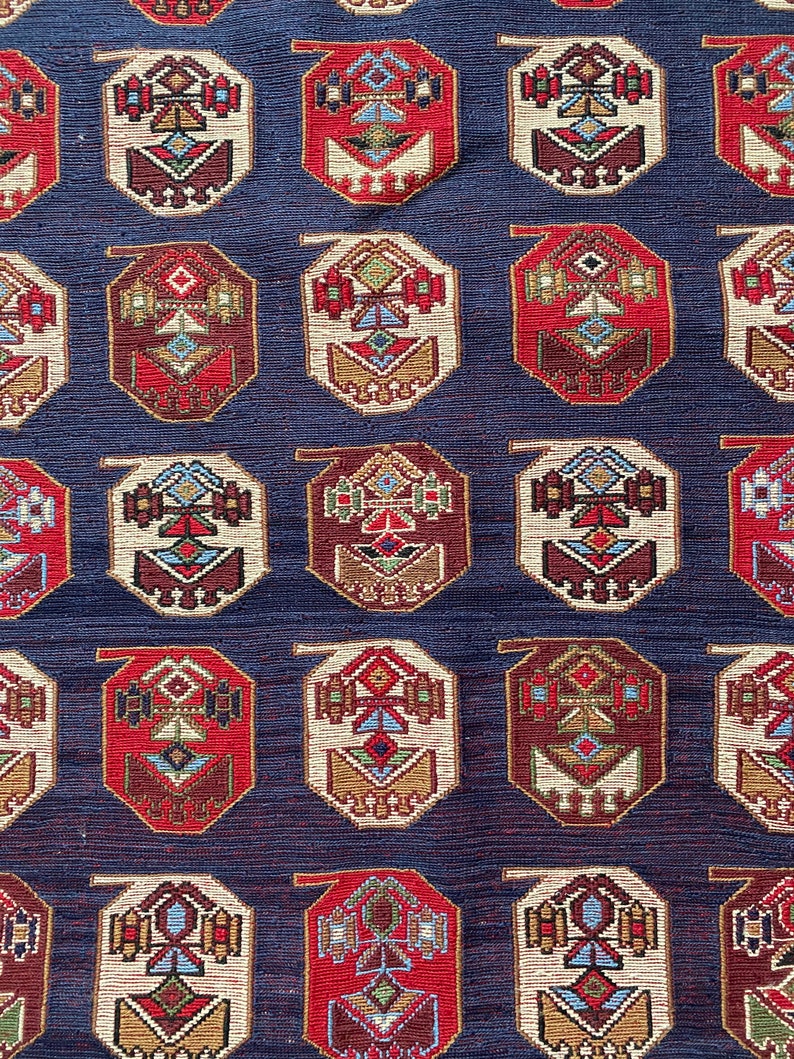Op de afbeelding: Een herhalend patroon van achthoekige vormen met ingewikkelde geometrische ontwerpen in tinten rood, wit, blauw, bruin en goud op een donkerblauwe achtergrond.
