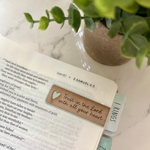 Könnte beinhalten: Ein Holz-Lesezeichen mit hellgrünem Hintergrund und einem weißen Herz. Das Lesezeichen trägt den Text "Trust in the Lord with all your heart".