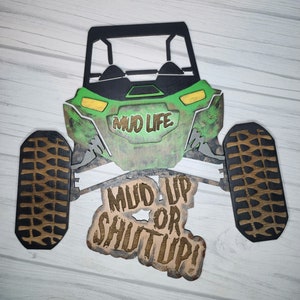 May include: Green and black wooden cutout of an off-road vehicle with the text "Mud Life" on the front and "Mud Up or Shut Up!" on the bottom.