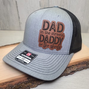 May include: A gray and black trucker hat with a brown leather patch that says "DAD in the streets, DADDY in the sheets".
