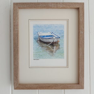 Könnte beinhalten: Gerahmtes Aquarellgemälde von zwei kleinen weißen und blauen Booten, die auf klarem türkisfarbenem Wasser schwimmen. Die Boote sind mit weißem Seil verbunden. Das Kunstwerk befindet sich in einem hellbraunen Holzrahmen und ist auf einem weißen Hintergrund montiert.