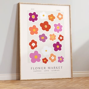 May include: A framed print with the text "Flower Market" and "Sapphic - Love - Lesbian" below. The print features a pattern of colourful flowers in shades of pink, red, orange, purple, and white.