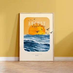 May include: A framed print featuring a sunset over the ocean with the text "AUGUST slipped away" and "CAUSE YOU WERE NEVER MINE".