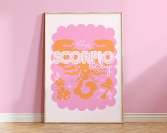 May include: A pink and orange print with a scorpion design and the text "SCORPIO baby". The print is framed in a light wood frame and is hanging on a pink wall.