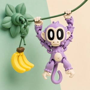May include: A whimsical purple monkey toy hanging from a green vine, with a bunch of yellow bananas attached to a green leaf. The monkey has large black eyes and is holding onto the vine with its hands.