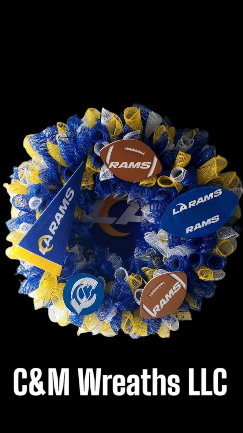 May include: A decorative wreath in blue, yellow, and white mesh, featuring football-shaped ornaments and a pennant, all bearing the "RAMS" logo. The wreath has a black background and the text "C&M Wreaths LLC".