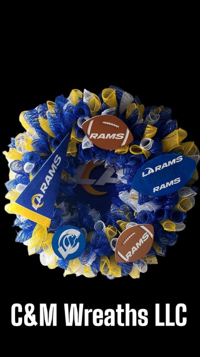 May include: A decorative wreath in blue, yellow, and white mesh, featuring football-shaped ornaments and a pennant, all bearing the "RAMS" logo. The wreath has a black background and the text "C&M Wreaths LLC".