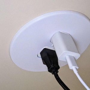 May include: A white ceiling outlet cover with two electrical cords plugged in. One cord is black and the other is white.