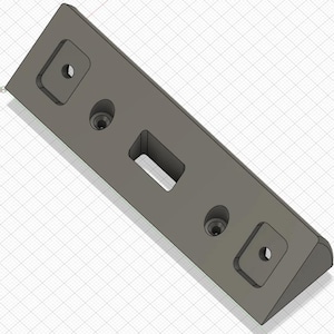 May include: A gray, rectangular component with a beveled edge. It features two square recessed areas with circular holes, a rectangular cutout, and two additional circular holes. The object is set against a grid background.