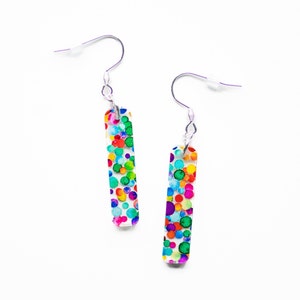 May include: A pair of silver dangle earrings with a rectangular, clear, colorful confetti design.