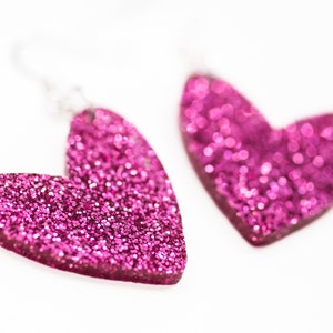 May include: A pair of pink glitter heart-shaped earrings.