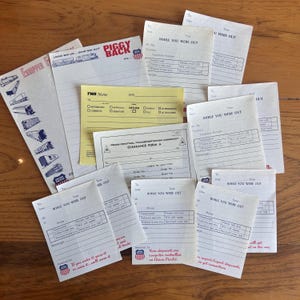 Può includere: Una collezione di documenti d'epoca, tra cui foglietti di messaggi "While You Were Out", un promemoria TWA e un modulo di sdoganamento Penn Central Transportation Company. I documenti presentano vari caratteri e loghi, con il logo Union Pacific su diversi articoli. La tavolozza dei colori è principalmente bianca, gialla e rossa.