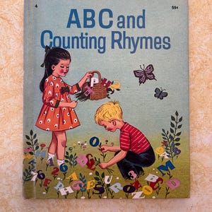 May include: A vintage children's book titled "ABC and Counting Rhymes" with a blue cover. The cover features two children, a girl in a red and white polka dot dress and a boy in a red and white striped shirt, surrounded by colorful letters and numbers.