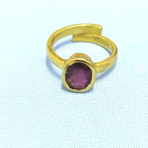 May include: A gold ring with a pink oval gemstone set in the center.