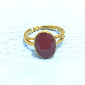 May include: A gold ring with a red oval-shaped stone set in the center.