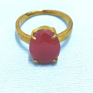 May include: A gold ring with a large, oval-shaped, pink gemstone.