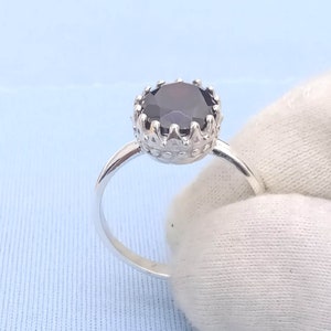May include: A silver ring with a black gemstone set in a crown-shaped setting.