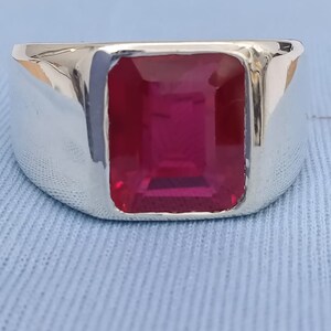 May include: A silver ring with a large, rectangular, red gemstone.