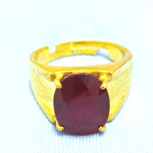 May include: A gold ring with a large, oval-shaped, dark red gemstone.