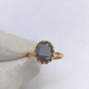 May include: A gold ring with a large, oval-shaped black gemstone set in a gold crown-like setting.