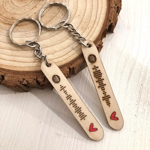 Può includere: Due portachiavi in legno con un cuore rosso e un design a codice a barre. I portachiavi sono attaccati a anelli portachiavi argentati.