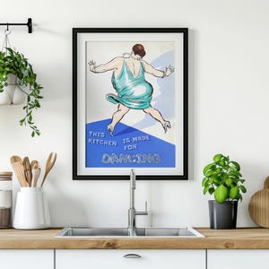 May include: A framed poster with a blue background and a woman in a turquoise dress dancing. The text on the poster reads "This kitchen is made for dancing."