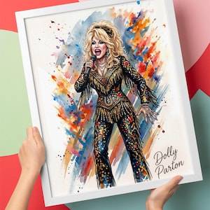 May include: A framed 14x11 watercolour-style print featuring a blonde singer in a black, gold-fringed outfit with floral accents, holding a microphone. The background consists of vibrant, multi-coloured paint splatters, and the text Dolly Parton is printed in the bottom right corner.