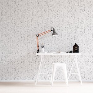 May include: A white desk with a white stool and a copper desk lamp. The desk is against a white wall with a black and white pattern. There is a small wooden house on the desk.