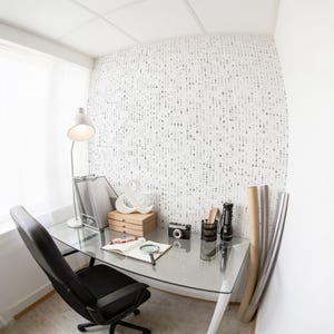 Pode incluir: Um espa&ccedil;o de escrit&oacute;rio dom&eacute;stico com uma secret&aacute;ria de vidro, uma cadeira de escrit&oacute;rio preta, um candeeiro branco, caixas castanhas, um sinal de e comercial branco, uma c&acirc;mara, uma lupa, um caderno aberto e uma parede com c&oacute;digo bin&aacute;rio.