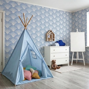 May include: A light blue fabric teepee tent with a small window, featuring a wooden pole frame. Inside are several plush pillows in pink, yellow, and teal. The room has blue and white patterned wallpaper, a white dresser, and a white easel.