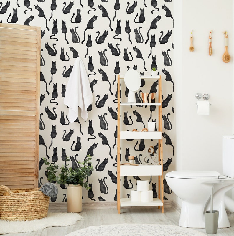 Puede incluir: Papel pintado con un patr&oacute;n repetitivo de siluetas de gatos negros sobre un fondo crema. Los gatos aparecen en diversas posturas sentadas y de pie, creando un dise&ntilde;o gr&aacute;fico monocrom&aacute;tico y denso en toda la superficie de la pared.